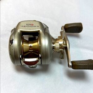 Team Daiwa-X 103HSD Fishing Reel with Gold and Silver Accents
